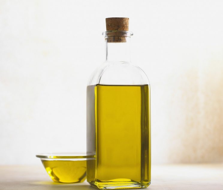 Bottle of ear drops next to an ear, demonstrating the proper application for earwax softening at home