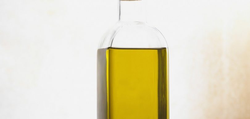 Bottle of ear drops next to an ear, demonstrating the proper application for earwax softening at home