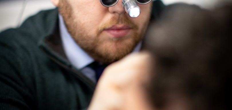 Audiologist performing professional ear wax removal with specialist equipment at Kensington Hearing London.