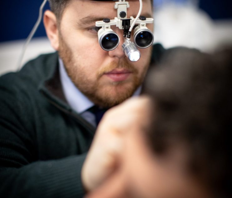 Audiologist performing professional ear wax removal with specialist equipment at Kensington Hearing London.