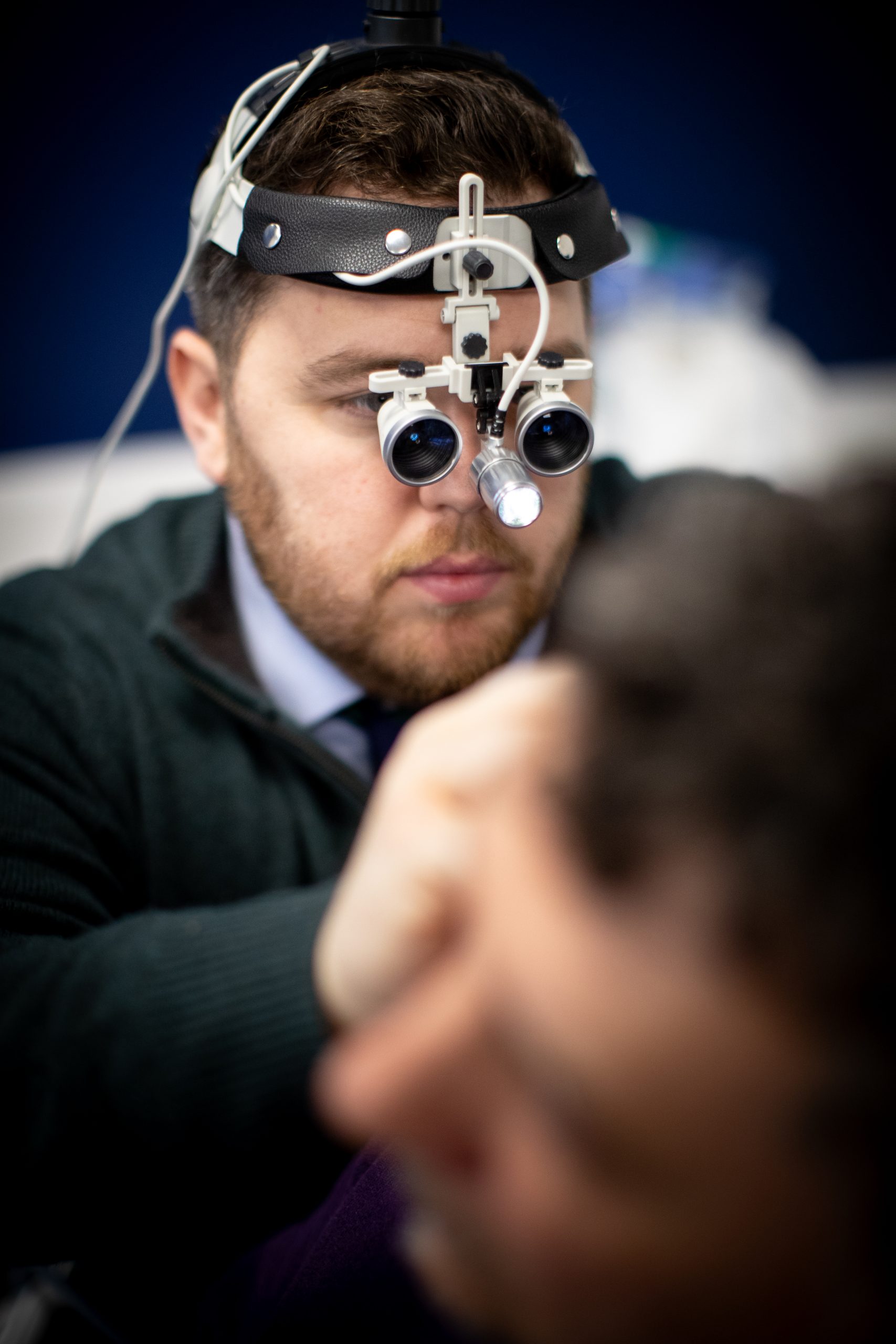 Audiologist performing professional ear wax removal with specialist equipment at Kensington Hearing London.